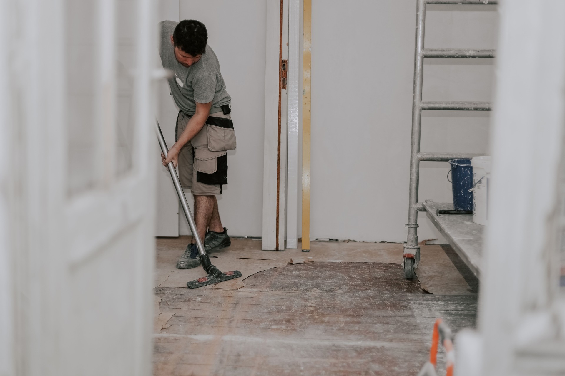 A young man vacuums the floor with a construction vacuum cleaner.