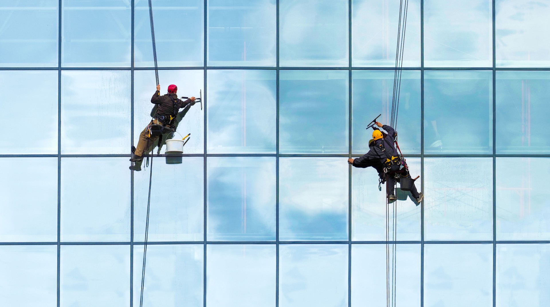 Group of workers cleaning windows service on high rise building. Workers cleaning glass curtain wall. Special job concept, panoramic view